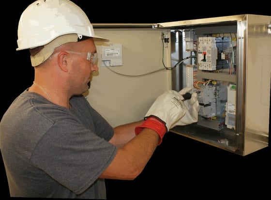 Control Panels & SCADA PRM technician in hard hat and safety glasses wiring a UL-certified control panel