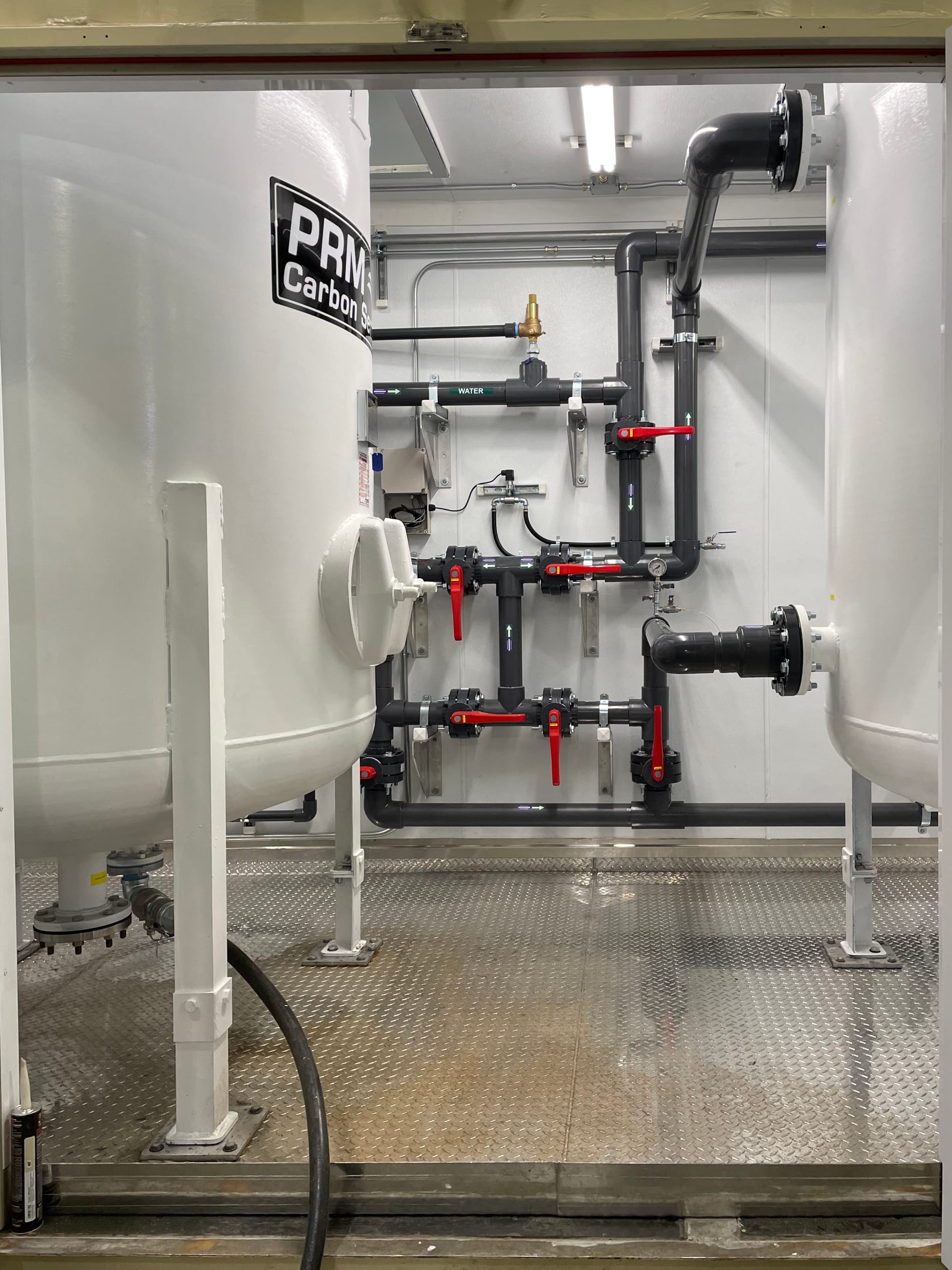 Dual PRM Carbon Services GAC vessels with valve manifold piping inside a Seabox container system