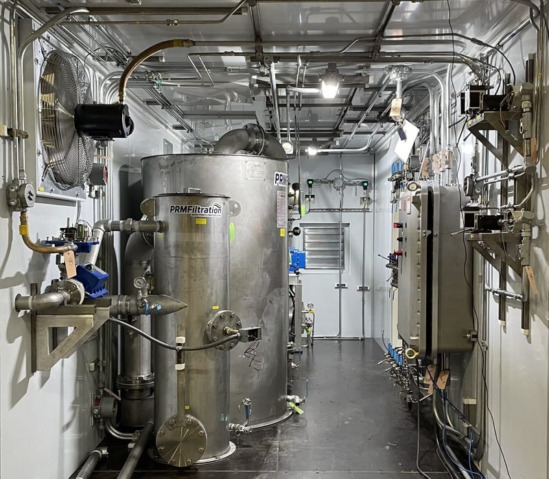 Interior of a PRM containerized remediation system with a stainless treatment vessel, heat exchanger, and piping