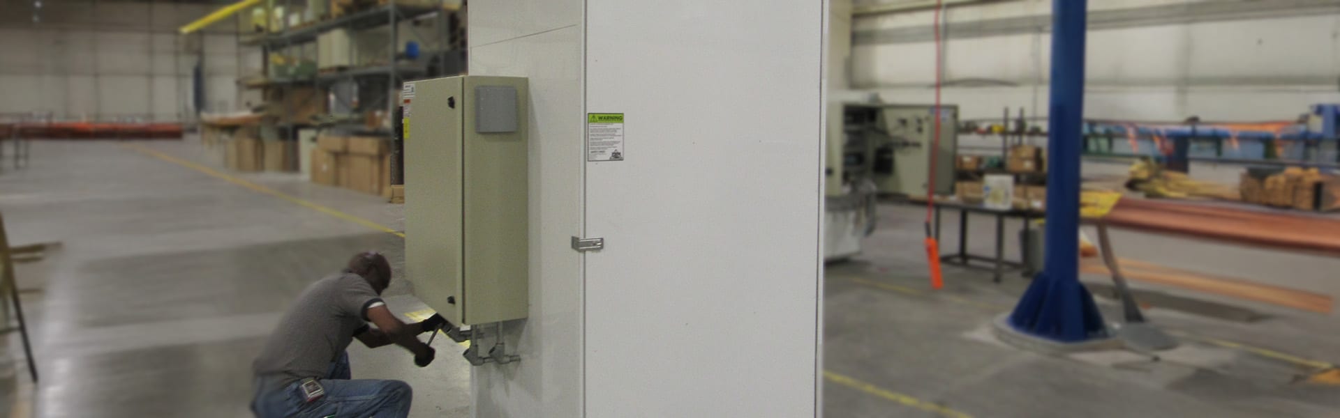 Technician installing a sub-slab depressurization vapor mitigation control panel on a building column