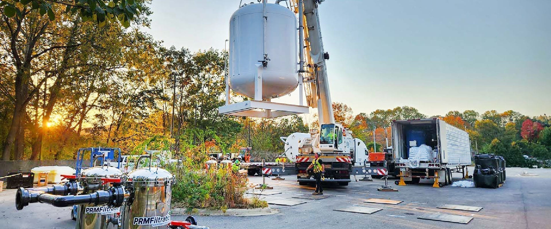 Crane setting a PRM treatment vessel onto a skid at a project site at sunset